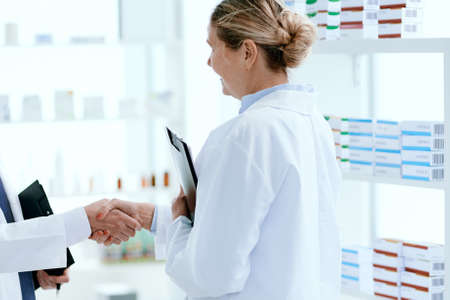 female pharmacist greeting shaking hands with her colleague.