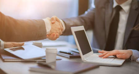 business colleagues shaking hands over a work Desk. close up.の写真素材