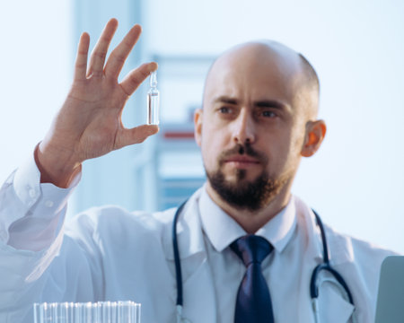 doctor is looking at the ampoule with the vaccine.の写真素材