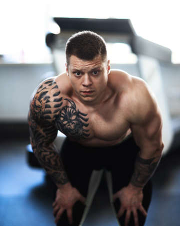 attractive young bodybuilder posing in a modern gym.