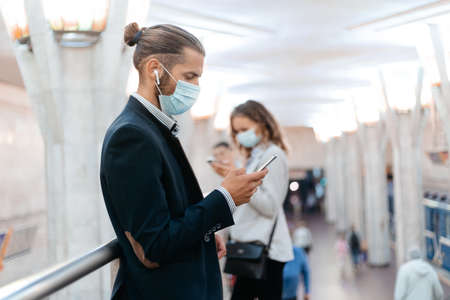 business man in a protective mask waiting for a train in the subway.