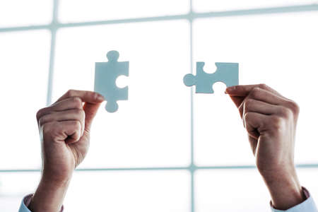 background image of puzzle pieces in the hands of a man.