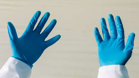 doctor is showing his hands in protective gloves .
