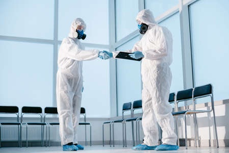 lab technicians in protective suits shaking hands.の写真素材