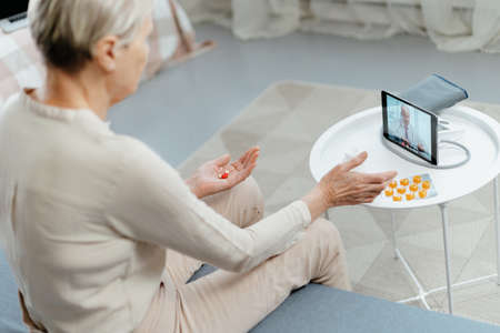 mature lady taking pills under the supervision of a doctor.の写真素材