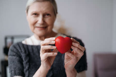 smiling mature woman with a red heart in her hands .