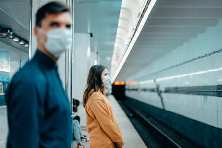 passengers in protective masks standing at the metro stationの写真素材