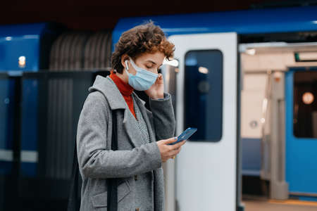 business woman with a smartphone walking into a subway train car.の写真素材