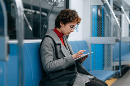 woman with a digital tablet sitting in an empty subway car.の写真素材