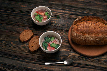 Plates of tomato soup and bread on a wooden board.