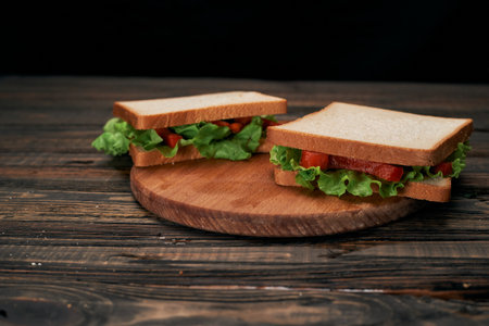 Two fresh tomato sandwiches on a wooden board.の写真素材