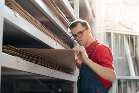 salesman of a flooring store with a sample of a laminate floor panel.
