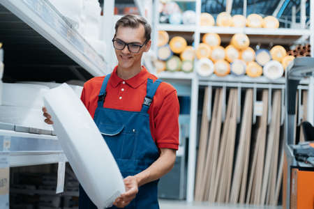 salesman with a roll of insulation in his hands standing in a hardware store.の写真素材