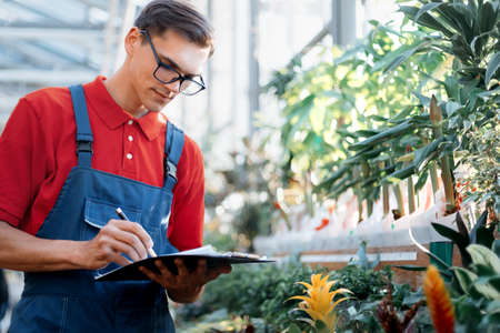 supervisor checks the markers on the plants in the garden center.