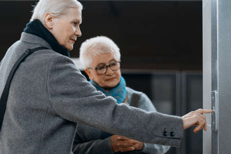 two mature women standing near the elevator.