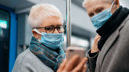 two female tourists taking selfies during a subway ride.の写真素材