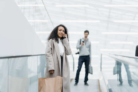 smiling woman with shopping standing on the escalator in the shopping center .の写真素材