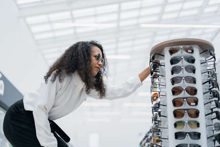 young woman looking at glasses on a shelf in an optometry store .の写真素材