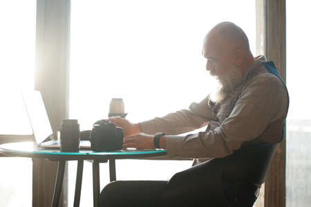 thoughtful male photographer works sitting at a table in a cafe .の写真素材
