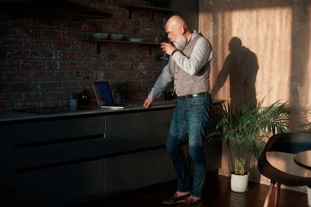 business man with a glass of wine checking his email in his kitchen .の写真素材