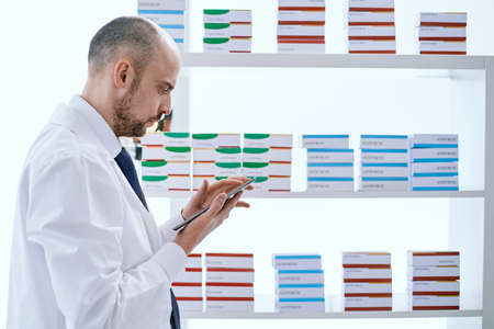 pharmacist with a digital tablet standing near a medicine showcase.の写真素材