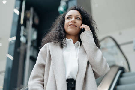 young woman talking on her smartphone standing on the escalator steps .