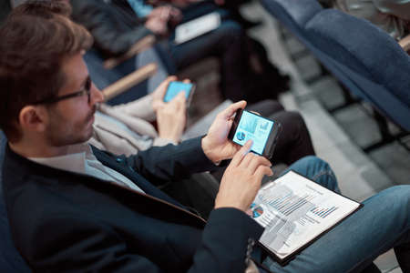 business man using his smartphone while sitting in the conference hall.