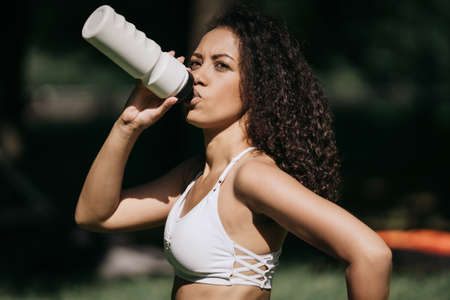 athletic young woman drinks water after a workout.