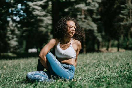 young woman meditates sitting on the grass in the park.の写真素材