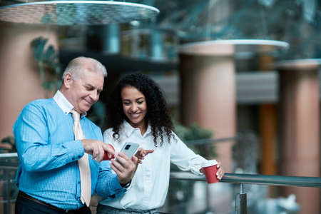 businessman using his smartphone standing in the lobby of a busiの写真素材