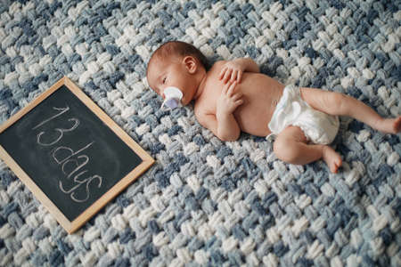 newborn baby with a pacifier lying next to a writing board .の写真素材