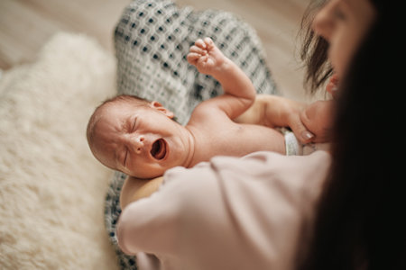 crying hungry newborn in the arms of his mother.の写真素材