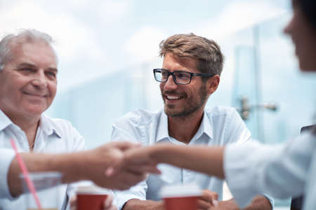 mature businessman greeting a young business woman with a handshake.の写真素材