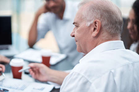 mature businessman discussing financial documents with a working group . close-up.