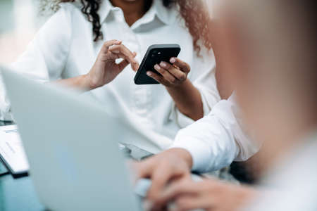 image of a businesswoman using her smartphone at an office meeting.の写真素材