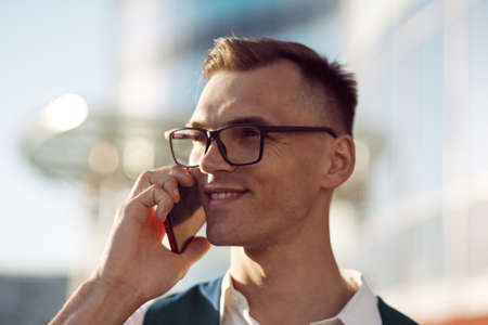 confident young man with a smartphone on a city background.