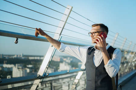 young man with a smartphone standing on the terrace of a busines