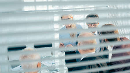 through the blinds. business team discussing business issuesの写真素材