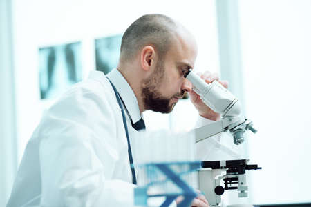 young scientist studying the obtained samples through a microscope
