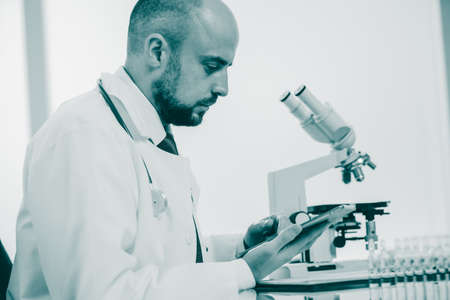 scientist using a digital tablet sitting at a laboratory table.の写真素材
