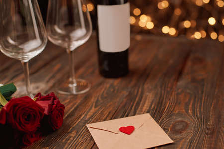 envelope with a valentine and a bouquet of roses on a wooden table.の写真素材