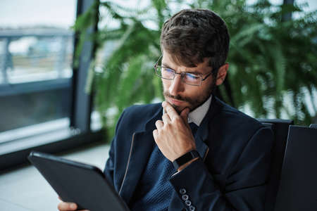business man thoughtfully looking at the screen of a digital tab