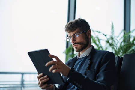 business man thoughtfully looking at the screen of a digital tabの写真素材