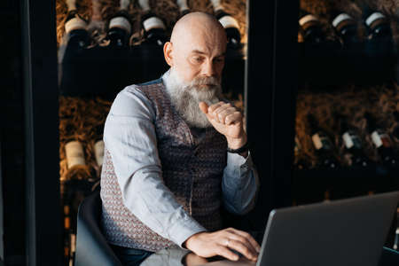 business owner of a liquor store sitting in front of an open laptop .の写真素材