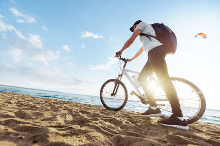 male tourist with a bicycle walking along a sandy beach .の写真素材