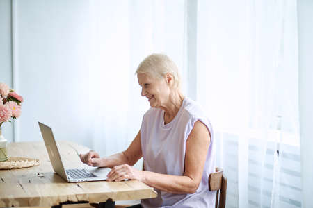 elderly woman using a laptop in a cozy living room.