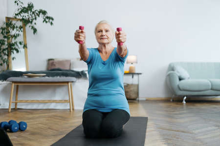 elderly woman doing an exercise with dumbbells with an online trainer.の写真素材