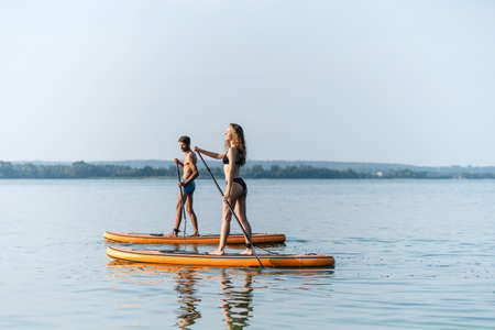 young couple in love standing on their sapboards and holding each others hands.の写真素材