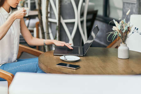 young woman is drinking coffee and looking through e-mail in a cozy cafe.の写真素材
