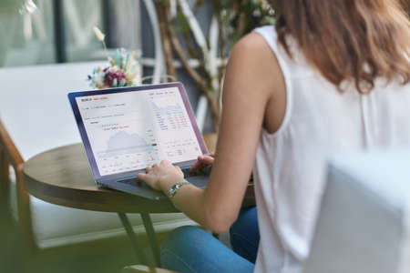 young woman using her laptop while sitting at a table in a cafe. rear view.